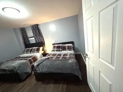 two beds in a small room with a door at Deluxe Apartment in Caledon
