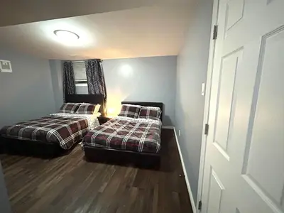two beds in a small room with a door at Deluxe Apartment in Caledon