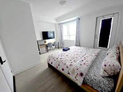 a bedroom with a bed and a window and a table at Modern Private Room Private Bathroom with King Bed with TV and Optional Balcony 10 minutes to Rogers Stadium Midtown Downtown Toronto in Toronto