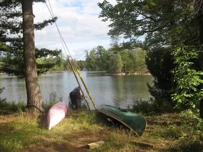 a person is lifting a canoe into a lake at Private Lakefront Family Cottage with Tennis Court in Kinmount