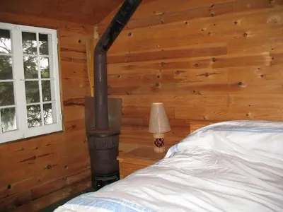 a bedroom with a fireplace in a wooden wall at Private Lakefront Family Cottage with Tennis Court in Kinmount