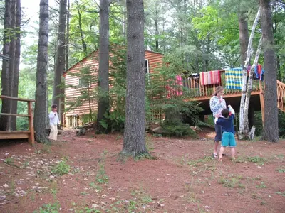 a woman and two children standing in front of a cabin at Private Lakefront Family Cottage with Tennis Court in Kinmount