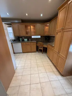 a kitchen with wooden cabinets and a tile floor at HOMESTAY NEXT TO SQUARE ONE MALL- 5 Mins Airport-24 HRS CHECKIN-MAJOR COST CUT in Mississauga