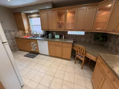 a kitchen with wooden cabinets and a table and a chair at HOMESTAY NEXT TO SQUARE ONE MALL- 5 Mins Airport-24 HRS CHECKIN-MAJOR COST CUT in Mississauga