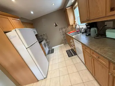 a kitchen with a white refrigerator and wooden cabinets at HOMESTAY NEXT TO SQUARE ONE MALL- 5 Mins Airport-24 HRS CHECKIN-MAJOR COST CUT in Mississauga