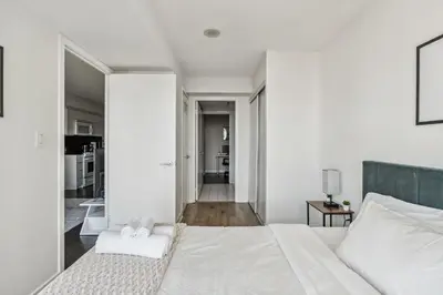 a white bedroom with a large bed and a hallway at Elegant Condo, Toronto Views , CityPlace Downtown in Toronto