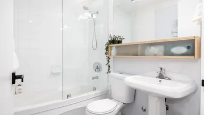 a white bathroom with a toilet and a sink at Modern 1BR Condo in Church Yonge Corridor in Toronto