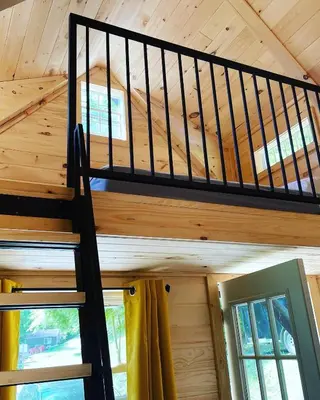 a staircase in a wooden cabin with windows at Wildwood Bunkies in Bailieboro