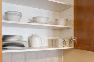 a cupboard filled with white dishes and cups and plates at Resort Style with Balcony Hot Tub and Full Kitchen in Edgar