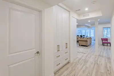 a white hallway with a door and a living room at Luxhome25 in Aurora