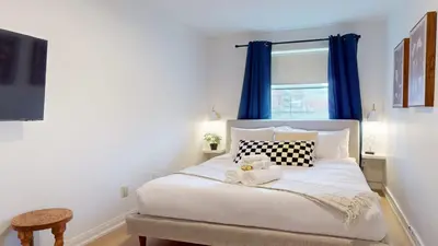 a bedroom with a white bed with blue curtains at Casa Hotel Elegant 2BR Suite in Leslieville in Toronto