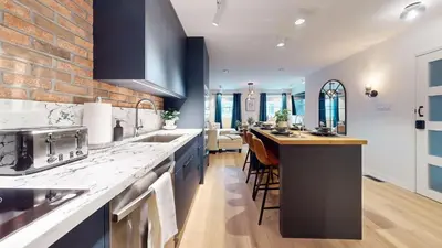 a kitchen with blue cabinets and a brick wall at Casa Hotel Elegant 2BR Suite in Leslieville in Toronto