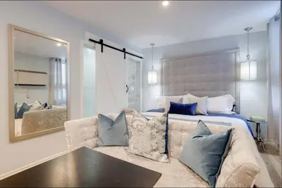 a bedroom with a bed and a couch and a mirror at Casa Hotel Stylish Suite with Patio in Leslieville in Toronto
