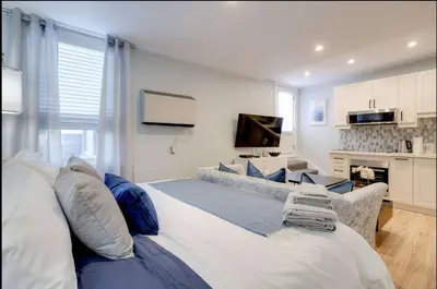 a large bed in a living room with a television at Casa Hotel Stylish Suite with Patio in Leslieville in Toronto