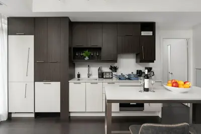a kitchen with white cabinets and a table with a bowl of fruit at 2BR 2BA Suite with Sofa Bed by Financial District in Toronto