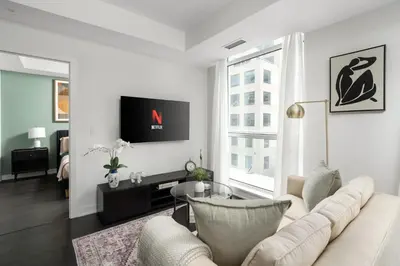 a living room with a white couch and a tv at 2BR 2BA Suite with Sofa Bed by Financial District in Toronto