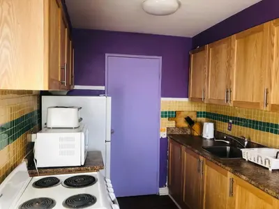 a kitchen with a stove and a purple wall at Earth Tone Suites in Pickering