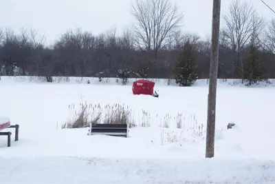 a red barn in a snow covered field with a pole at Liftlock Guest House in Peterborough