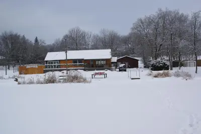 a house covered in snow in front of a field at Liftlock Guest House in Peterborough
