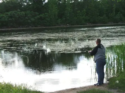 a man standing next to a body of water fishing at Liftlock Guest House in Peterborough