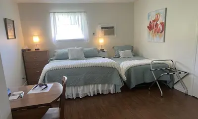 a bedroom with two beds and a table and a window at Liftlock Guest House in Peterborough