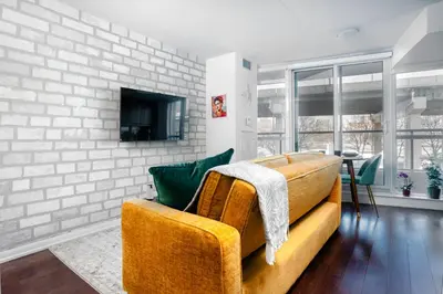 a living room with a couch and a tv at Downtown Cozy 1BR Condo- Steps from Lake & King street in Toronto