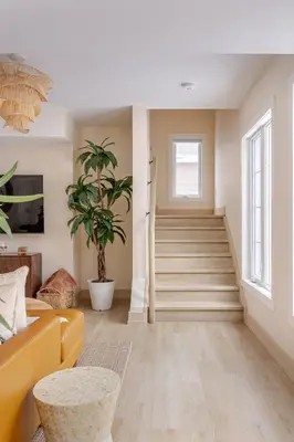 a living room with a yellow couch and stairs at The California Sunset in St. Catharines