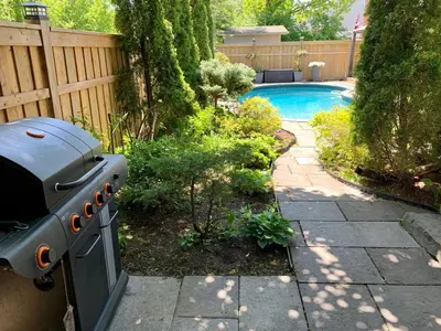 a grill in a garden next to a swimming pool at Garden Suite with Pool and Sauna in Brampton