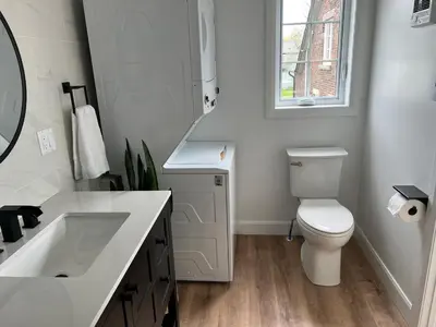 a bathroom with a toilet and a sink and a window at Garden Suite with Pool and Sauna in Brampton