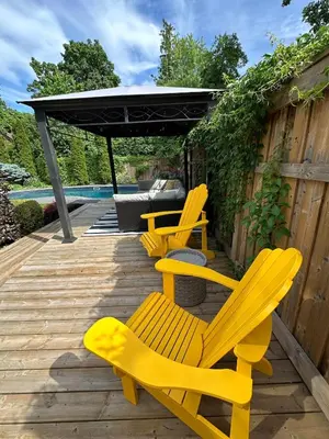 three yellow chairs sitting on a wooden deck at Garden Suite with Pool and Sauna in Brampton