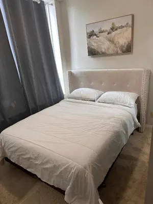 a bed with white sheets and pillows in a bedroom at Private Cozy Room in Mississauga