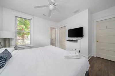 a white bedroom with a white bed and a flat screen tv at The Balsam - 36 Farm View in Cherry Valley