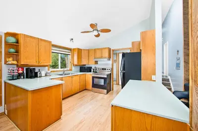 a kitchen with wooden cabinets and a black refrigerator at PRIVATE COTTAGE GETAWAY On LAKE SIMCOE in Brechin