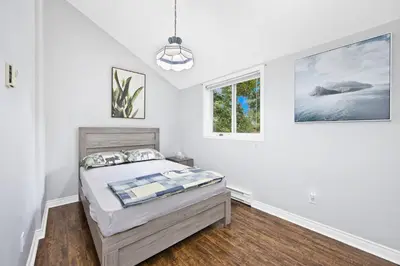 a white bedroom with a bed and a window at PRIVATE COTTAGE GETAWAY On LAKE SIMCOE in Brechin