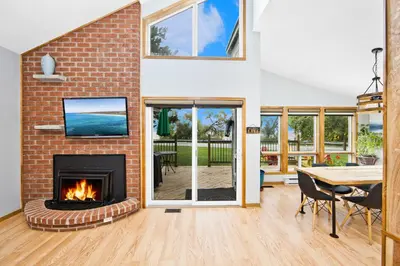 a living room with a brick fireplace and a table and chairs at PRIVATE COTTAGE GETAWAY On LAKE SIMCOE in Brechin