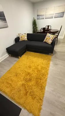 a black couch with a yellow rug in a living room at Brand new 2 bedroom basement apartment in Ajax