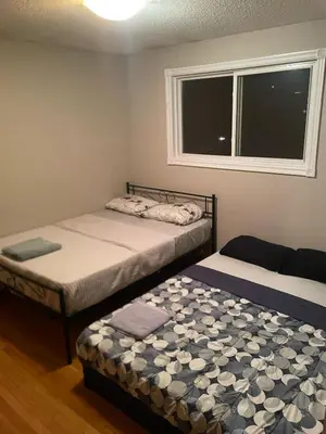 two beds in a room with a window at Upper Level Cheap Room For 3 People- 24 Hrs Checkin-Walking to Bus,Grocery, Plaza in Kitchener