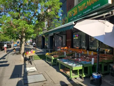 a street with a fruit stand on the sidewalk at Toronto Little Italy Guest House in Toronto
