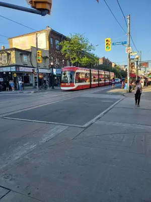 a red tram on a city street with a traffic light at Toronto Little Italy Guest House in Toronto