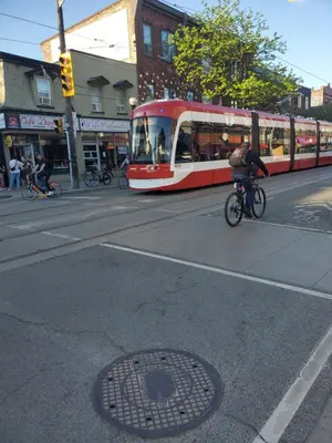 a person riding a bike on a street with a streetcar at Toronto Little Italy Guest House in Toronto