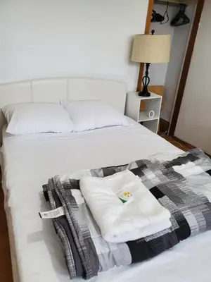 a bed with two towels and a blanket on it at Toronto Little Italy Guest House in Toronto