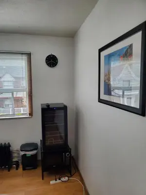 a living room with a television and a clock on the wall at Toronto Little Italy Guest House in Toronto