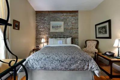 a bedroom with a bed and a stone wall at The Breadalbane Inn in Fergus