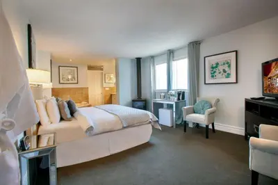 a bedroom with a bed and a chair and a television at The Breadalbane Inn in Fergus