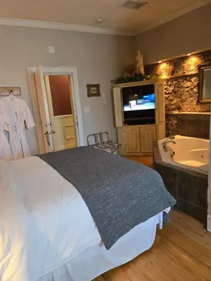 a bedroom with a bed and a tub and a television at The Breadalbane Inn in Fergus