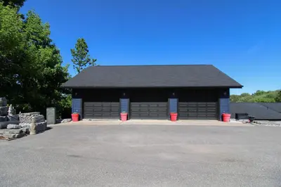 a black garage with two red trash cans in front of it at Lux Lakeside Escape Slps 20 with Pool, Golf Sim, Hot Tub, Karaoke, Gym and Sauna in Peterborough