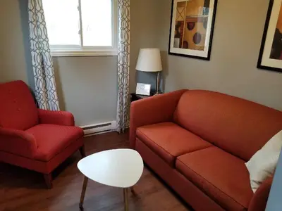 a living room with a couch and a chair and a table at Westlake Cottage - Hillier Lodge in Wellington