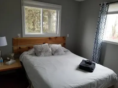 a bedroom with a white bed with a window at Westlake Cottage - Hillier Lodge in Wellington