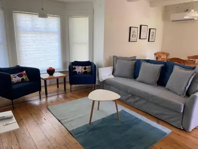 a living room with a gray couch and blue chairs at Westlake Cottages - Tulip Tree in Wellington