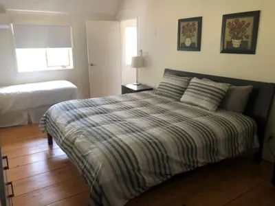 a bedroom with a bed with a striped comforter and a window at Westlake Cottages - Tulip Tree in Wellington